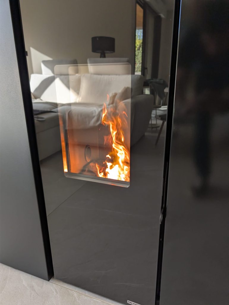 Détail de la façade noire du poêle Palazzetti Tiffany et de sa vitre laissant voir la flamme