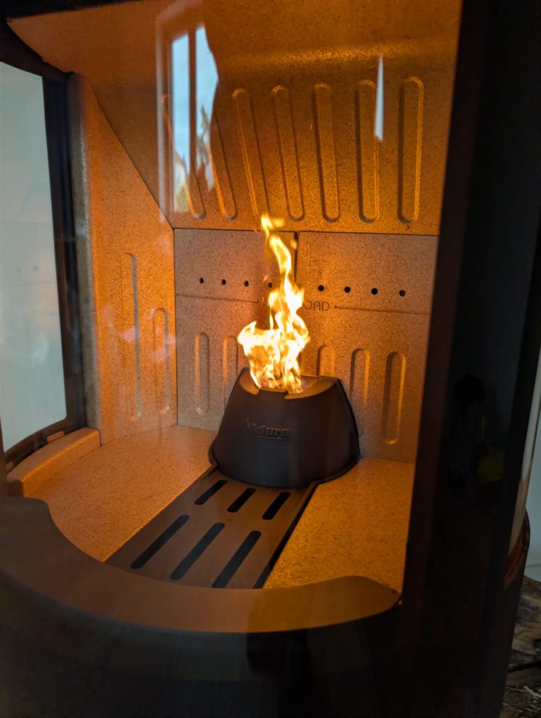 Gros plan du foyer du poêle Aduro en fonctionnement, flamme au-dessus du brasier à granulés